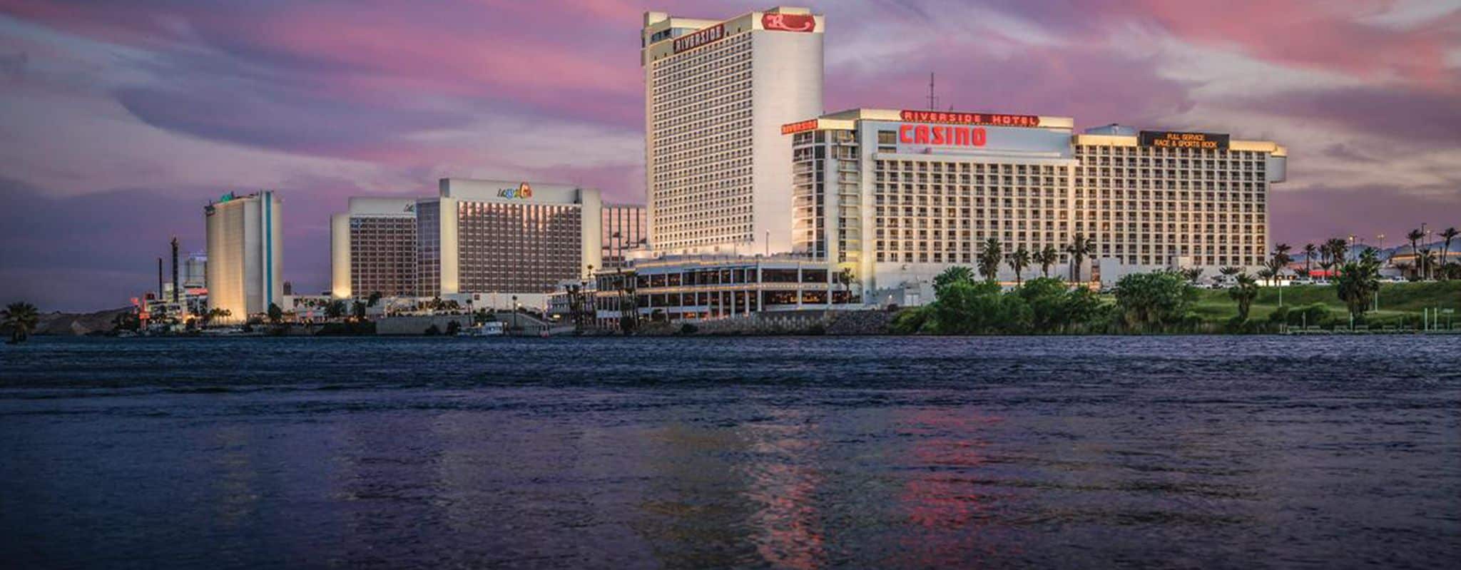A river reflects the pink and purple sunset sky, with several casino hotels lining the far bank.
